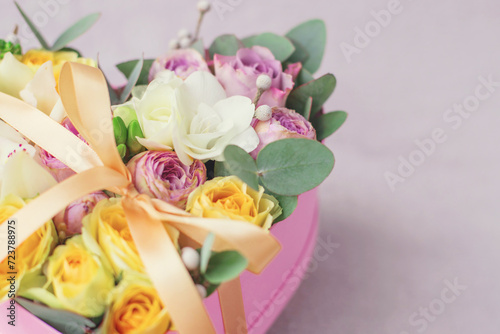 Pink flowers in a pink heart box. White orchid  purple and yellow roses with bunch. Womans day . Flowers bouquet on background . Romantic concept. Copy space