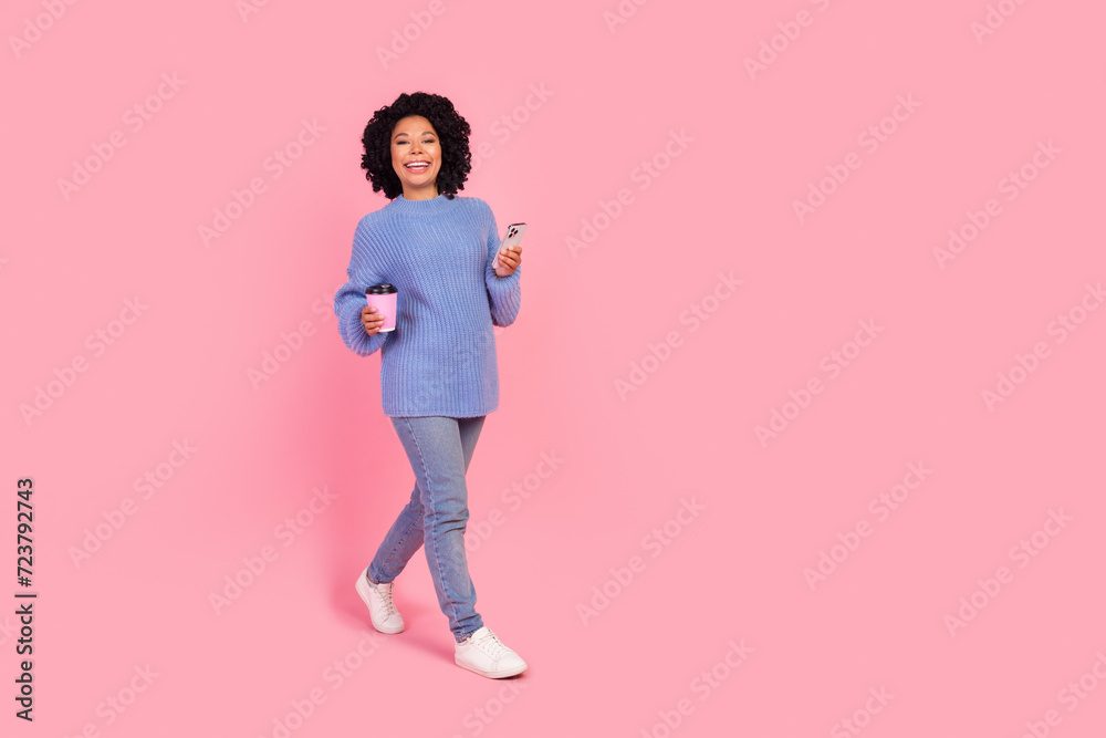 Full length photo of cute sweet woman wear pullover enjoying coffee to go communicating device empty space isolated pink color background Full length photo of cute sweet woman wear pullover enjoying coffee to go communicating device empty space isolated pink color background
