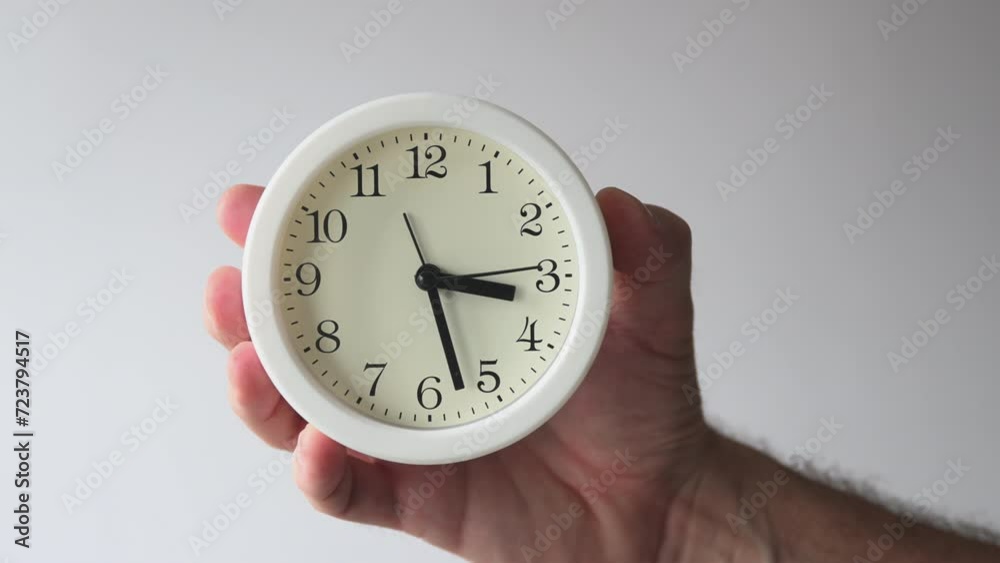 Man holding white plastic alarm clock, passing of time concept Man holding white plastic alarm clock, passing of time concept