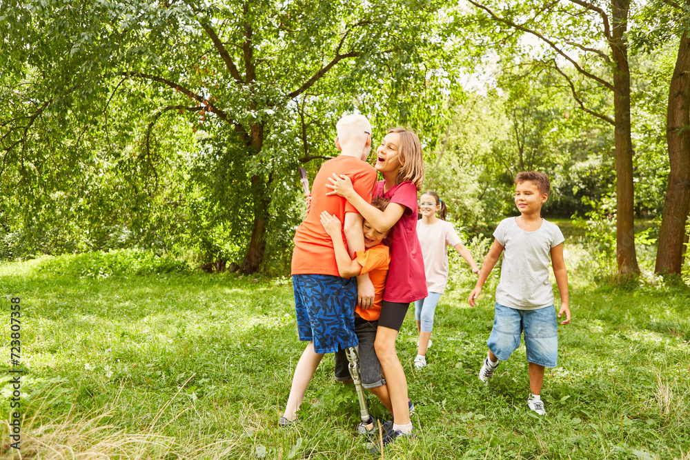 Obraz premium Children embracing disabled friend at park