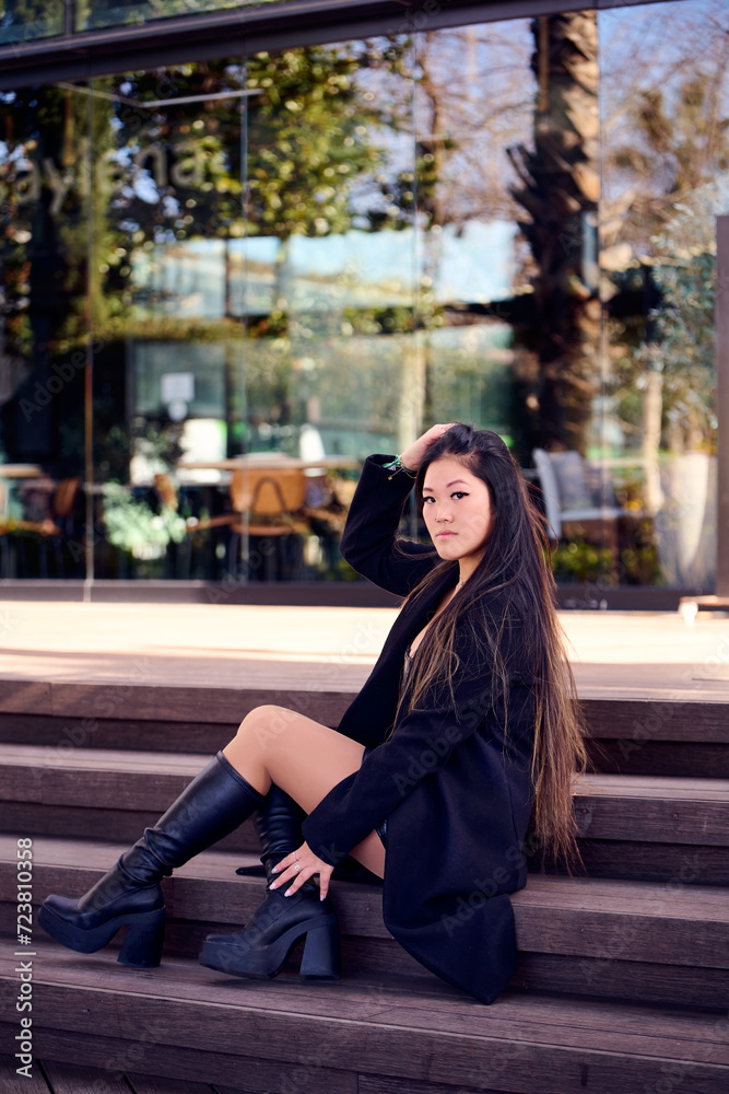 Fototapeta premium Portrait of a beautiful young Asian woman in a black coat and boots
