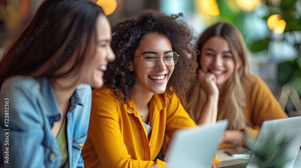 Obraz premium Young women laughing together at a cafe with laptops.