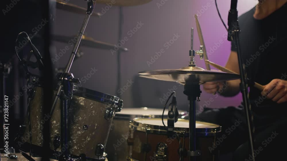a young attractive guy plays a drum kit. Strikes a cymbal, rehearses. Performance of a rock band, hobby. A man is learning music. Male professional holds drumsticks in hands. Drum set in slow motion