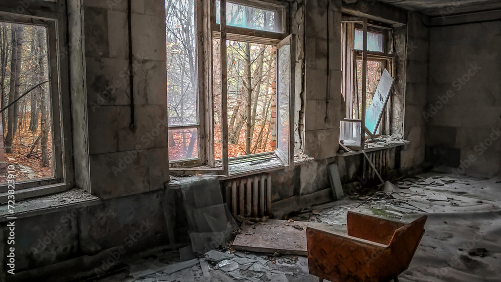 chair opposite the window in the room of an old ruined abandoned house in Pripyat in Ukraine