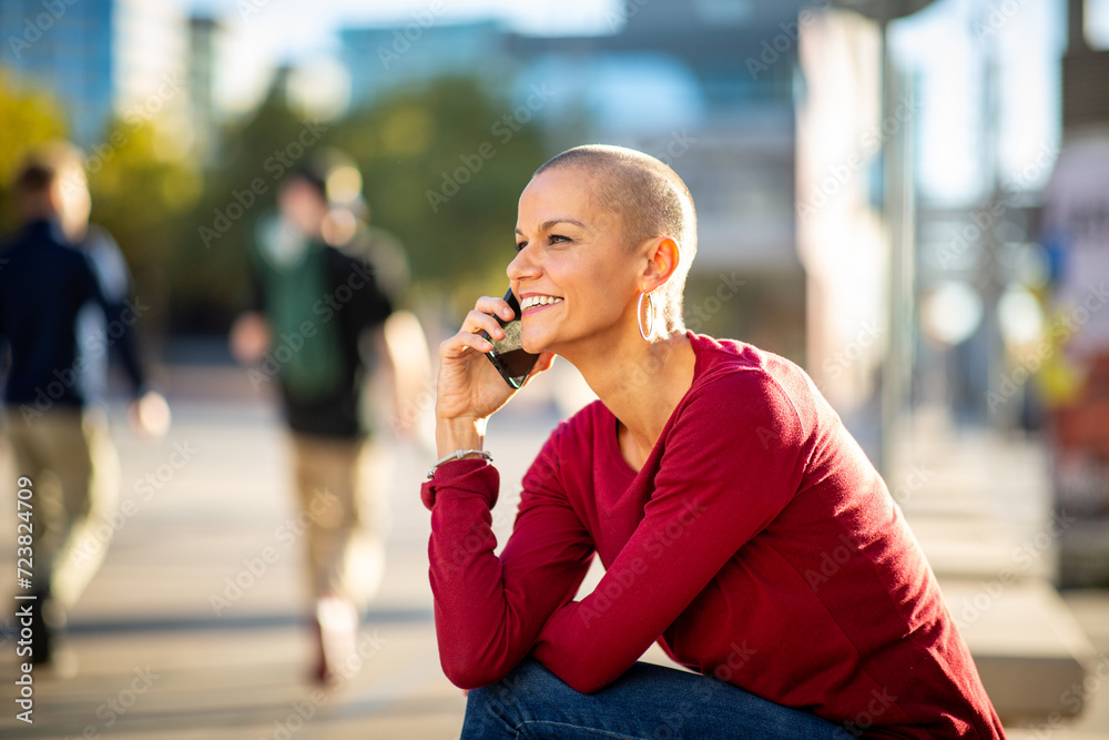 woman with shaved head talking with cellphone in city woman with shaved head talking with cellphone in city