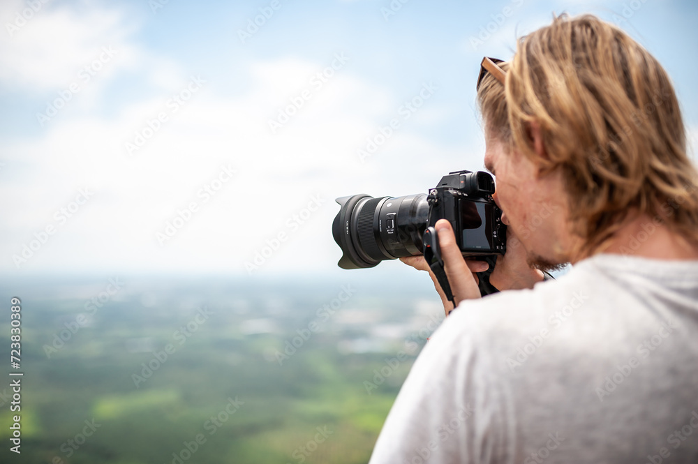 Obraz premium Man photographer shooting landscape standing on a viewpoint