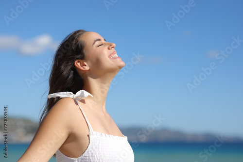 Happy woman breathing and laughing on the beach