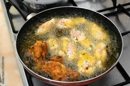 Frying chicken wings in hot vegetable palm oil in the pan