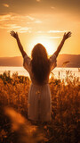 Happy young woman with arms outstretched enjoying beautiful sunset on the lake