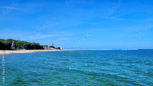 Blue sea and blue sky. in the background there is a city with a lighthouse and a Ferris wheel ending with a pier.