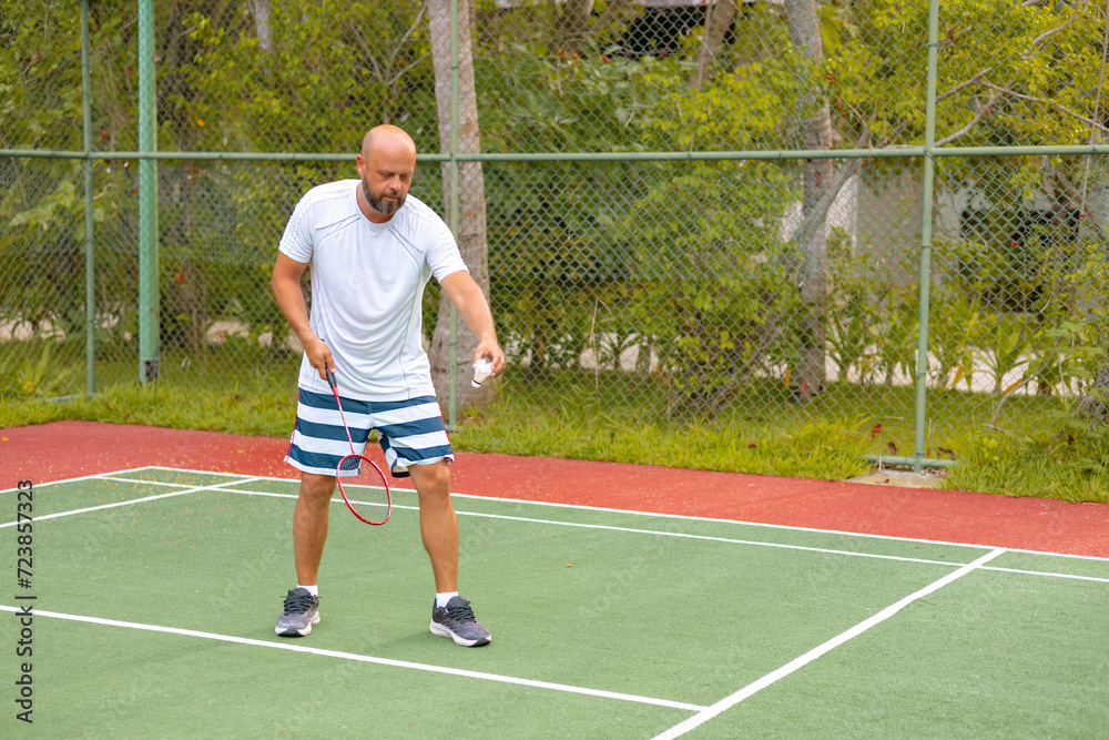 man plays badminton outdoors in the fresh air, throws a shuttlecock and holds a racket, an island in the Maldives, active recreation and sports man plays badminton outdoors in the fresh air, throws a shuttlecock and holds a racket, an island in the Maldives, active recreation and sports