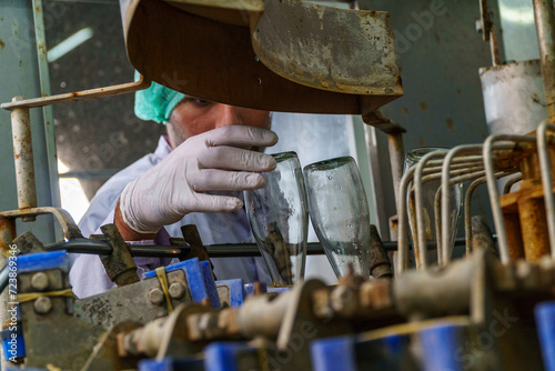 A factory worker inspects bottles on a beverage production line.