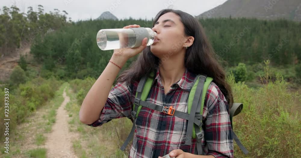 Hiking woman, drinking water and bottle on adventure for hydration, detox or wellness in nature. Girl, bush trekking and liquid for health in forest, woods or outdoor for fitness, training or summer Hiking woman, drinking water and bottle on adventure for hydration, detox or wellness in nature. Girl, bush trekking and liquid for health in forest, woods or outdoor for fitness, training or summer