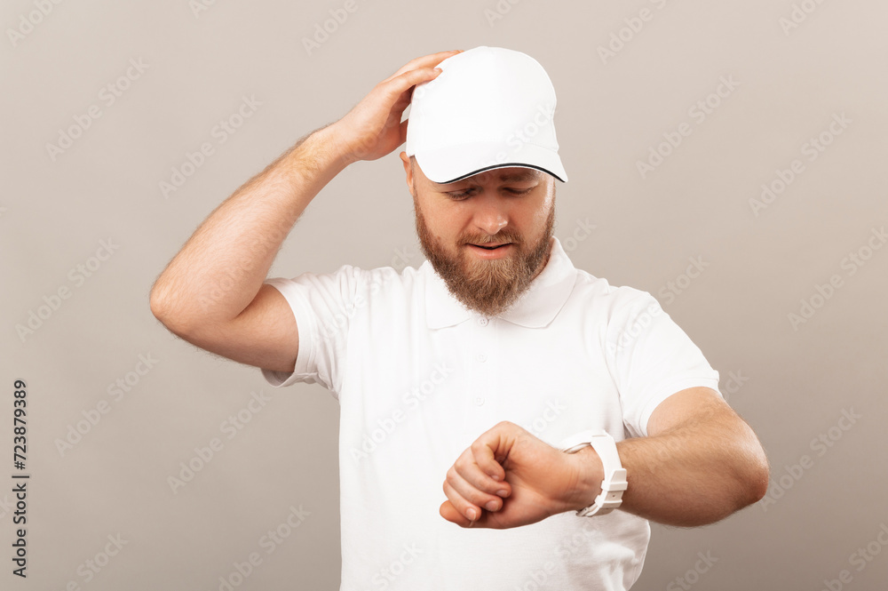 Handsome young bearded man wearing white uniform looking at his watch and realises he is late.