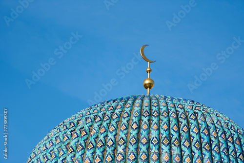 The dome of an Islamic mosque with the symbol of the hilal crescent moon in the blue sky photo