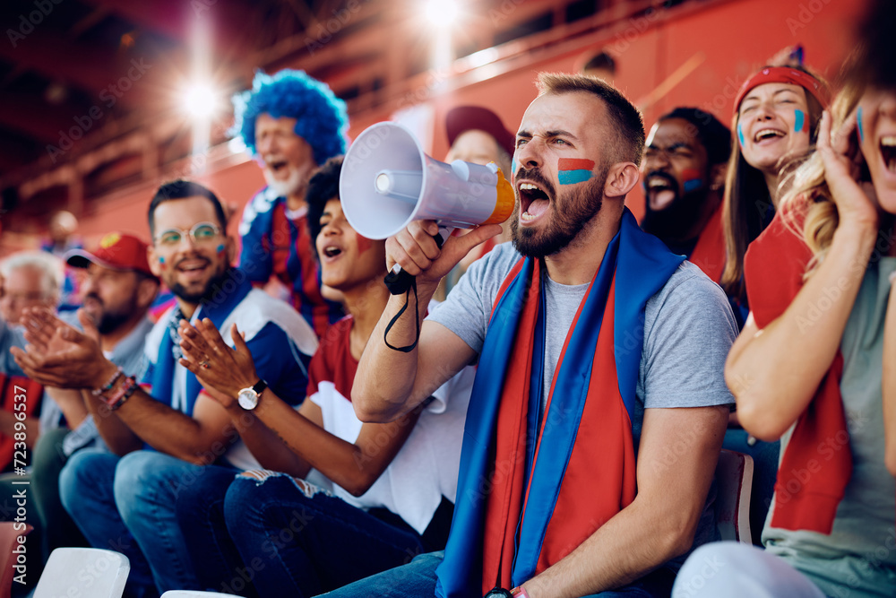 Obraz premium Sports fan shouting through megaphone during match at stadium.