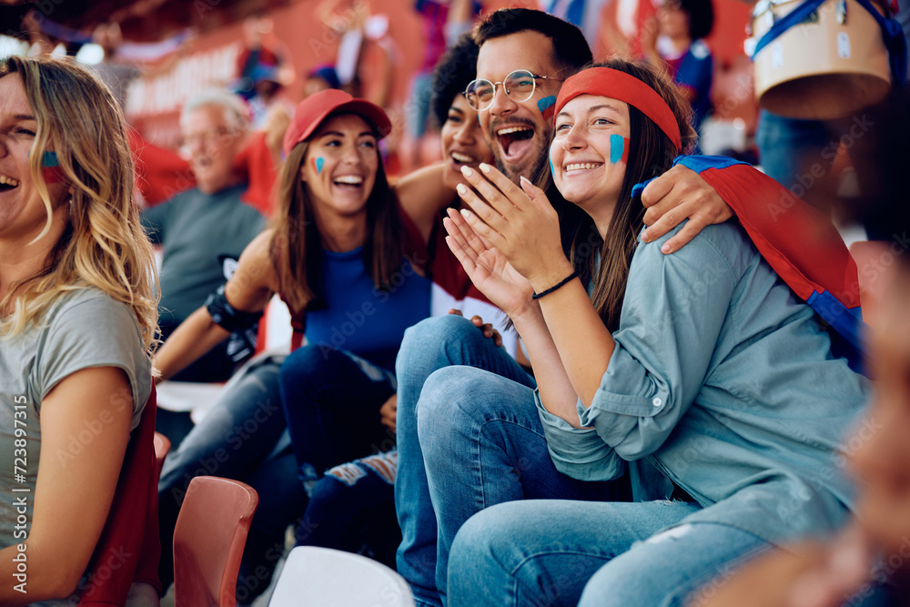 Obraz premium Multiracial group of cheerful friends celebrating during sports game at stadium.