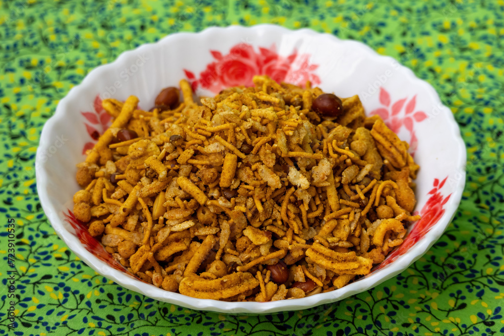 Bombay mixed Chanachur on a floral white bowl, green background Bombay mixed Chanachur on a floral white bowl, green background