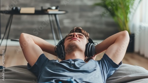 Teenager boy relaxing while lying in bed in headphones and listening to the music. Lost in melodies, he escapes to a world of rhythm. photo