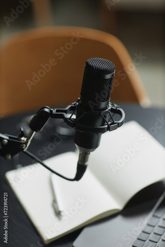 Vertical close up shot of black condenser microphone prepared for podcast interview in recording studio