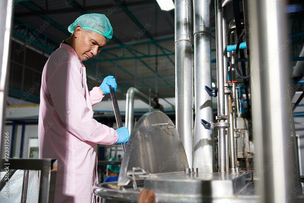 worker stirring water on large industrial pot in the factory