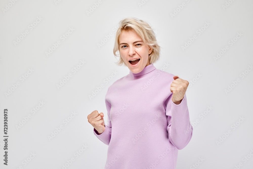 Portrait of smiling face blond young woman clenching fists and rejoicing, celebrating victory isolated on white studio background, advertising banner. Portrait of smiling face blond young woman clenching fists and rejoicing, celebrating victory isolated on white studio background, advertising banner.