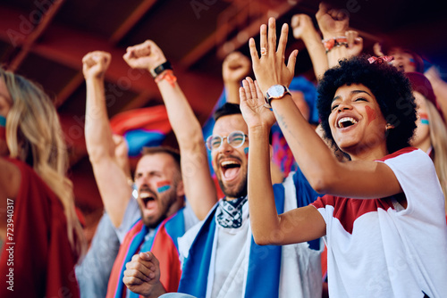 Fototapet Happy black woman cheering with group of fans during sports match at stadium