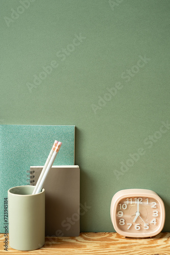 Obraz na płótnie Stationery office supply. Notebook, pencil holder, clock on wooden desk. green wall background. workspace w salonie