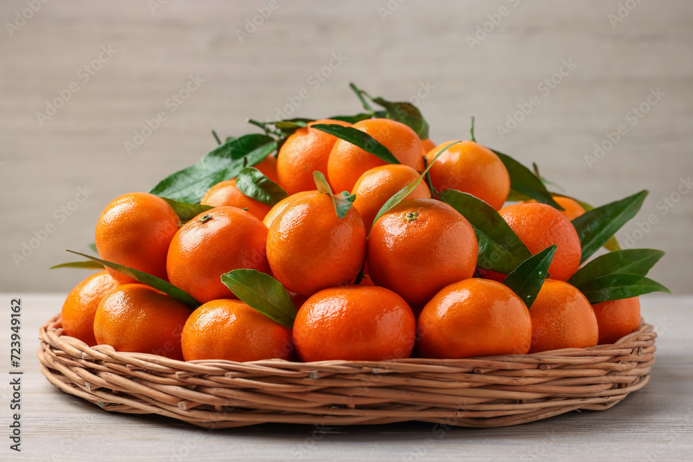 Fresh ripe juicy tangerines and green leaves on white wooden table Fresh ripe juicy tangerines and green leaves on white wooden table