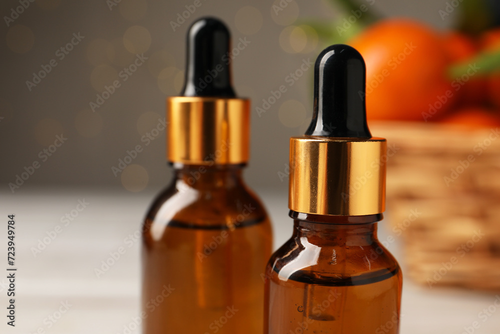 Bottle of tangerine essential oil on blurred background, closeup