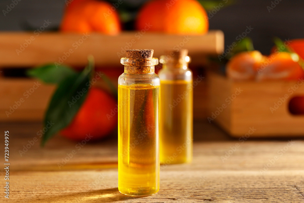 Bottles of tangerine essential oil on wooden table, closeup Bottles of tangerine essential oil on wooden table, closeup