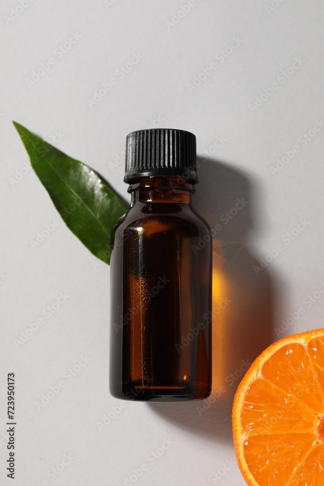 Aromatic tangerine essential oil in bottle, leaf and citrus fruit on grey table, top view Aromatic tangerine essential oil in bottle, leaf and citrus fruit on grey table, top view