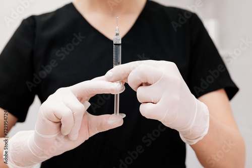 Hand holding a syringe  the syringe is filled with clear liquid. Injection procedure. Lip augmentation  close-up. Advertising concept for facial care