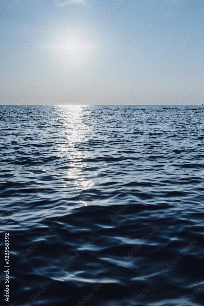 Obraz premium beautiful seascape. The blue sea goes into the horizon. reflection of the sun in the sea.vertical photo of the sea