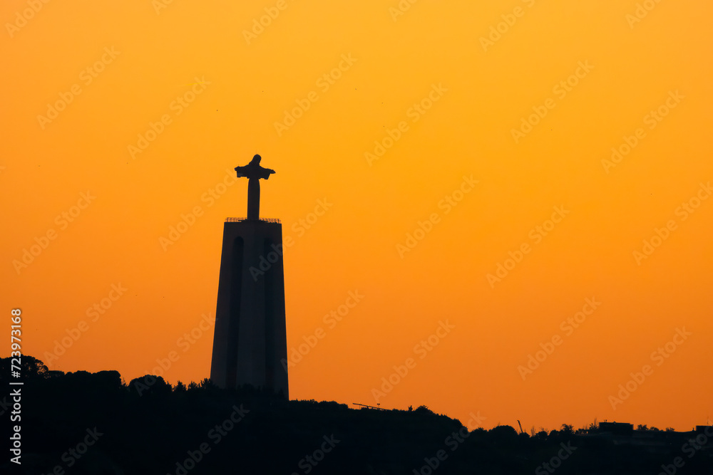 The silhouette of the iconic Christ monument looking over the Tagus River at sunset, Lisbon, Portugal
