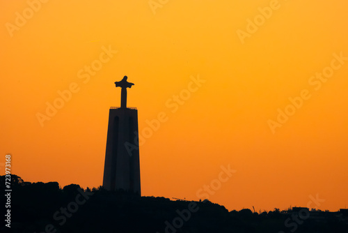 The silhouette of the iconic Christ monument looking over the Tagus River at sunset, Lisbon, Portugal