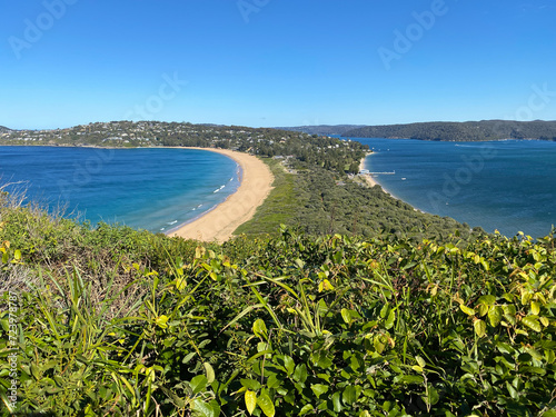 Narrow peninsular surrounded by water on two sides. Panorama of the ocean. View of the mountain and the island's coastline. Palm beach, Australia. Beach that divides the ocean. photo