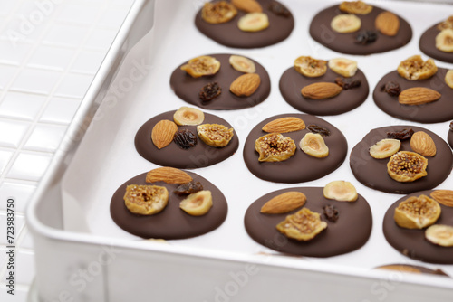 homemade chocolate mendiants with traditional toppings; almonds, raisins, hazelnuts, fig. French Christmas sweets.