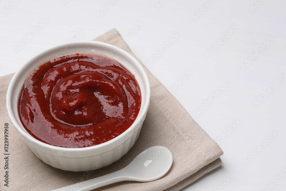 Organic ketchup in bowl and spoon on white table, space for text. Tomato sauce Organic ketchup in bowl and spoon on white table, space for text. Tomato sauce