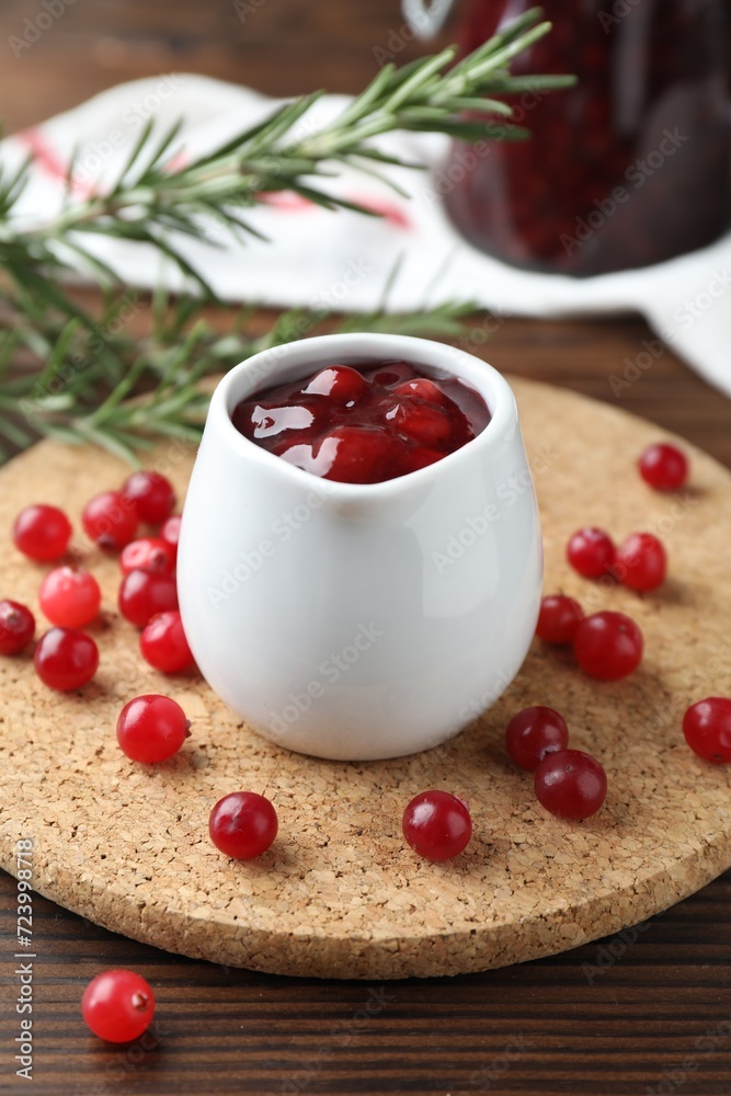 Cranberry sauce in pitcher and fresh berries on wooden table, closeup Cranberry sauce in pitcher and fresh berries on wooden table, closeup