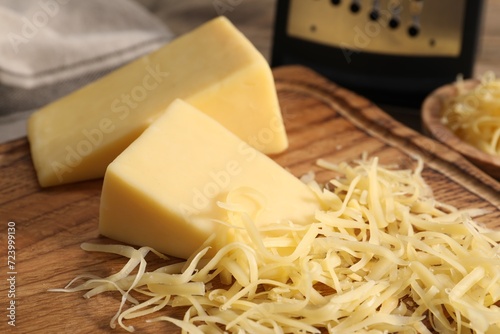 Grated and whole pieces of cheese on wooden table, closeup