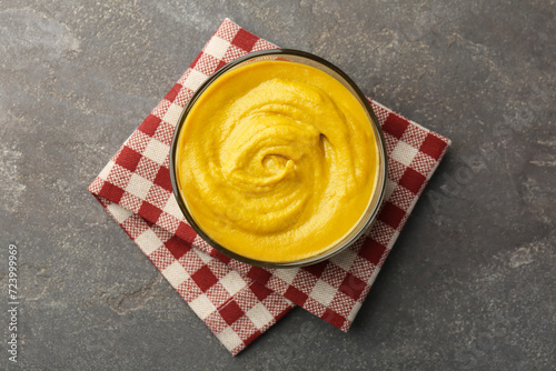 Tasty mustard sauce in bowl on grey textured table, top view