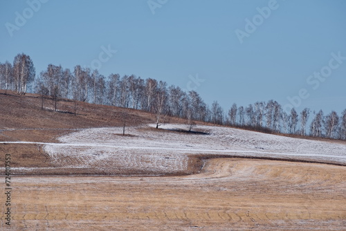 Russia. Krasnoyarsk Territory. Morning view of the relief hills with sparse vegetation dusted with the last spring snow.