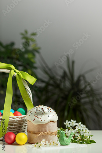 traditional Orthodox Easter cake and colored eggs in a wicker basket, on a white table in the middle plan. happy Easter