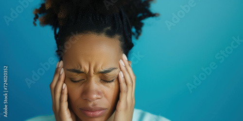 An African girl, closing her eyes, holds her head with her hands, demonstrating a headache. Medical care concept