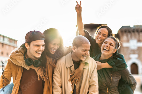 Smiling friends having fun walking on city street at sunset - Group of young people enjoying at vacation together - Friendship concept with guys and girls hanging outside on a sunny day photo