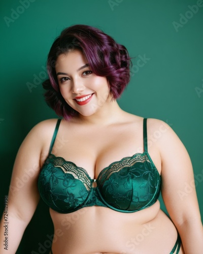 A woman with purple hair and red lipstick poses in a plus-size, green lingerie set.