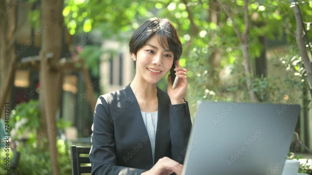 テラス席で電話をする30代女性会社員