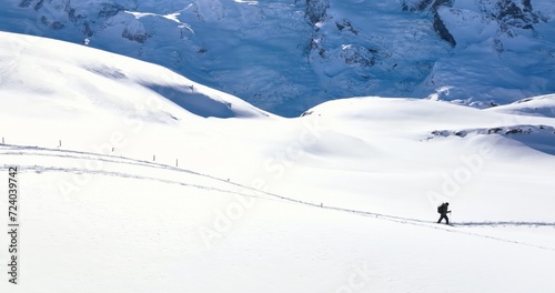 Panoramic landscape of Young man tourist hiker walking in snow shoes. Successful climber hiking up to mountain top swiss alps, Switzerland. Active travel lifestyle winter outdoor activities journey.
