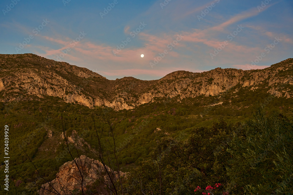 paisaje de montaña al amanecer con la luna y nubes